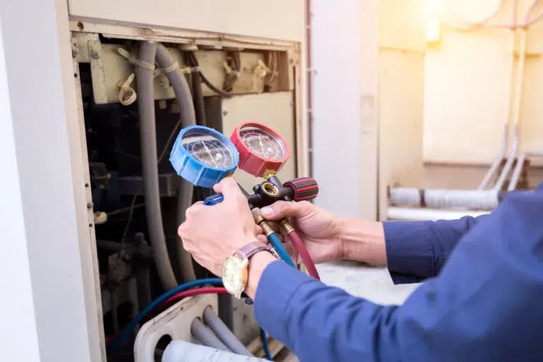 A man measures the temperature of a furnace while holding a hose, ensuring proper operation and safety.