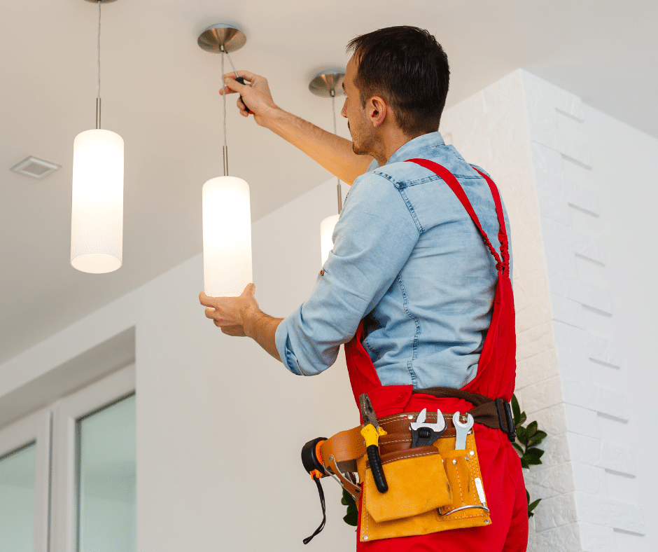 An electrician repairs a light fixture 